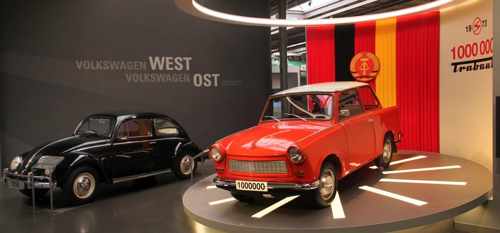 Ausstellungsbereich im August Horch Museum mit einem roten Trabant 601 als 1.000.000stes Exemplar und einem schwarzen VW Käfer im Hintergrund, ergänzt durch DDR-Symbolik und Beschriftung. Foto: Oliver Göhler
