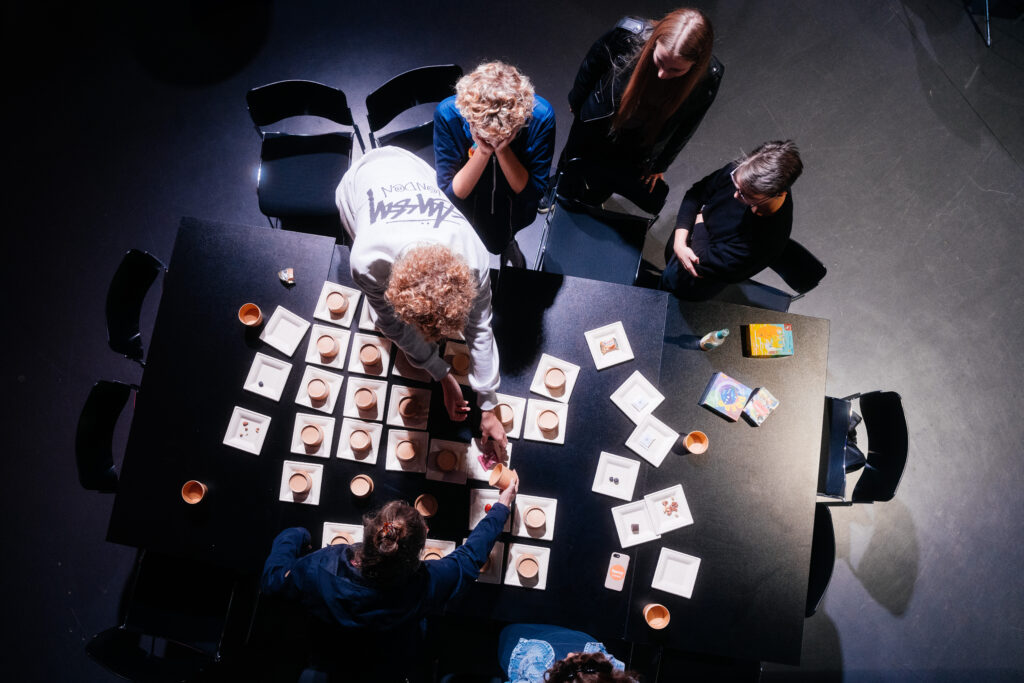 Draufsicht, Menschen sind über einen Tisch gebeugt und spielen ein Brettspiel